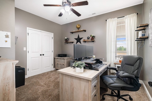 home office featuring baseboards, ceiling fan, visible vents, and dark carpet