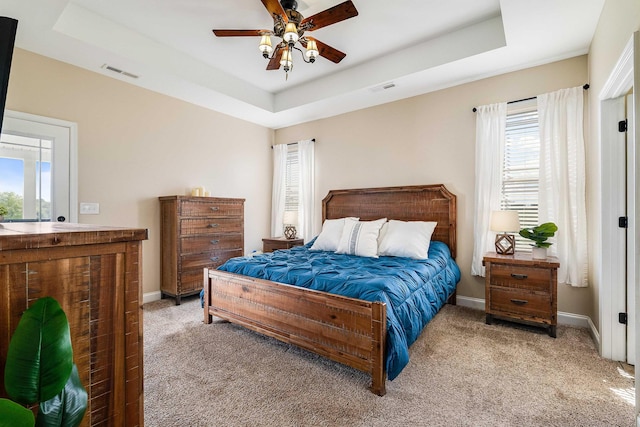 bedroom with carpet floors, multiple windows, a tray ceiling, and visible vents