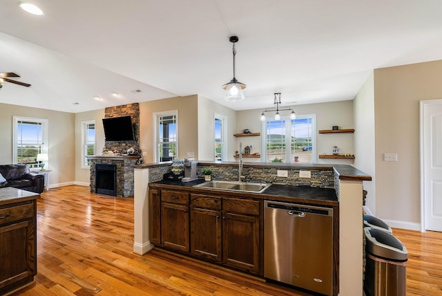 kitchen featuring a sink, dark countertops, stainless steel dishwasher, and open floor plan