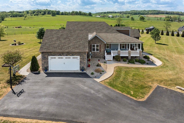 view of front of property with roof with shingles, a rural view, driveway, and stone siding