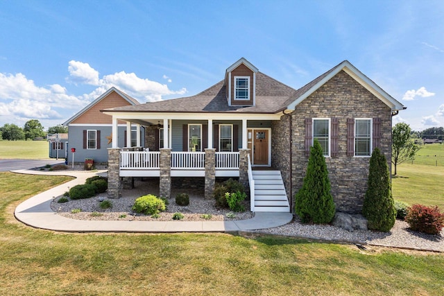 craftsman-style home with covered porch, a front yard, stairway, a shingled roof, and stone siding