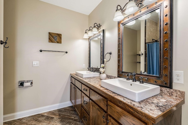 full bath with baseboards, a sink, and double vanity