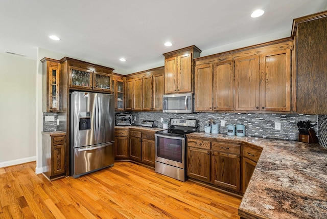kitchen featuring backsplash, visible vents, appliances with stainless steel finishes, baseboards, and light wood-style flooring
