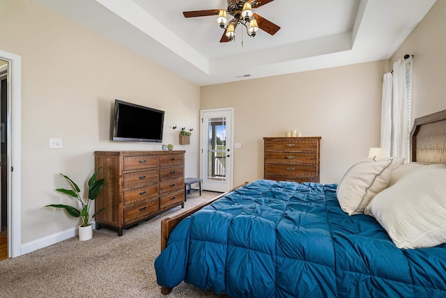 carpeted bedroom featuring ceiling fan, visible vents, baseboards, access to outside, and a tray ceiling
