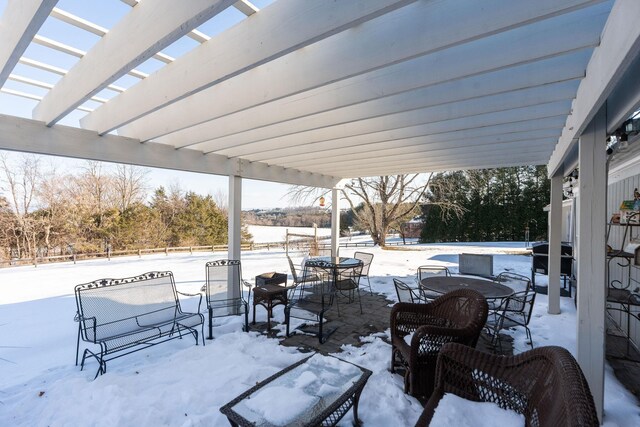 snow covered patio with area for grilling and a pergola