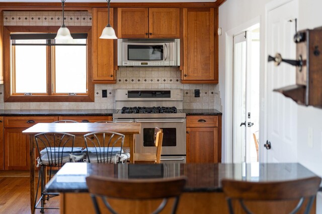 kitchen with pendant lighting, decorative backsplash, light hardwood / wood-style floors, and appliances with stainless steel finishes