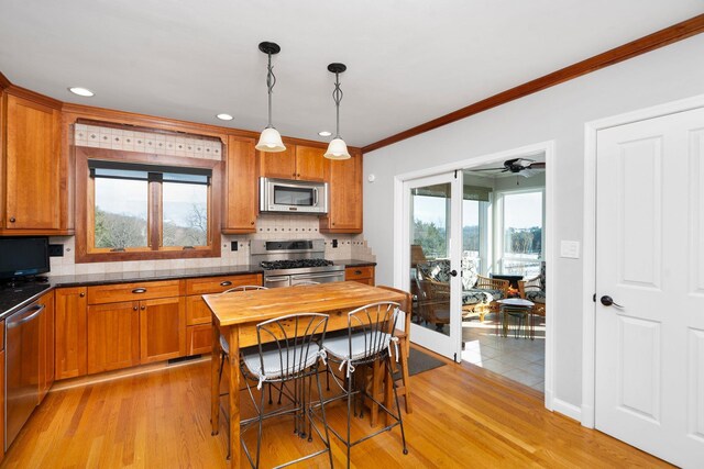 kitchen featuring stainless steel appliances, hanging light fixtures, light wood-type flooring, and decorative backsplash