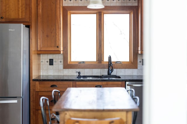 kitchen with backsplash, appliances with stainless steel finishes, sink, and dark stone countertops