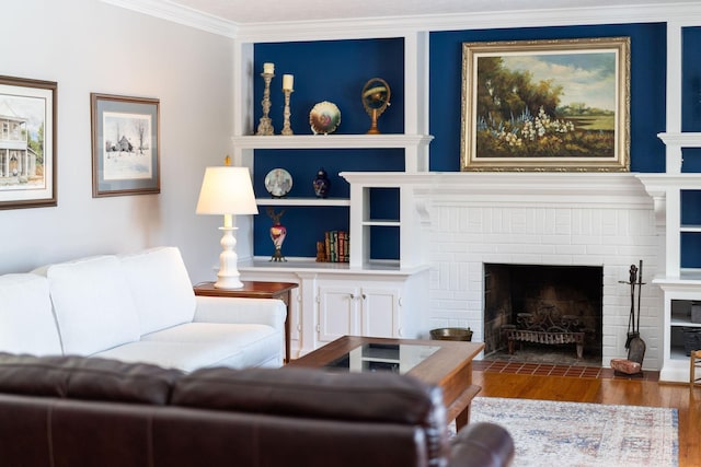 living room featuring built in shelves, ornamental molding, wood-type flooring, and a fireplace