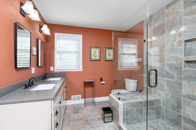 bathroom featuring vanity, a shower with shower door, and toilet