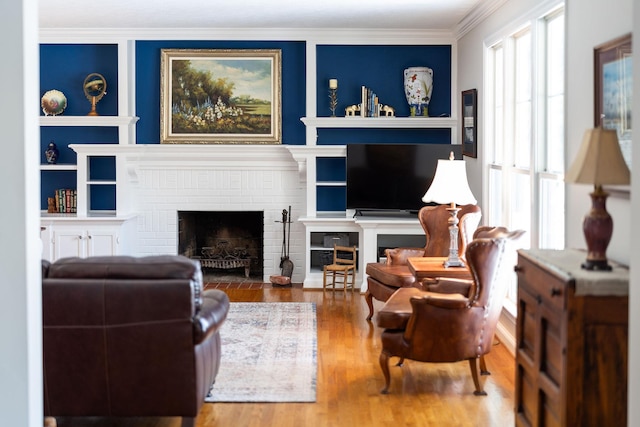 living room featuring a brick fireplace, hardwood / wood-style flooring, and ornamental molding