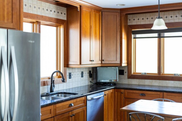 kitchen featuring decorative light fixtures, sink, decorative backsplash, dark stone counters, and stainless steel appliances