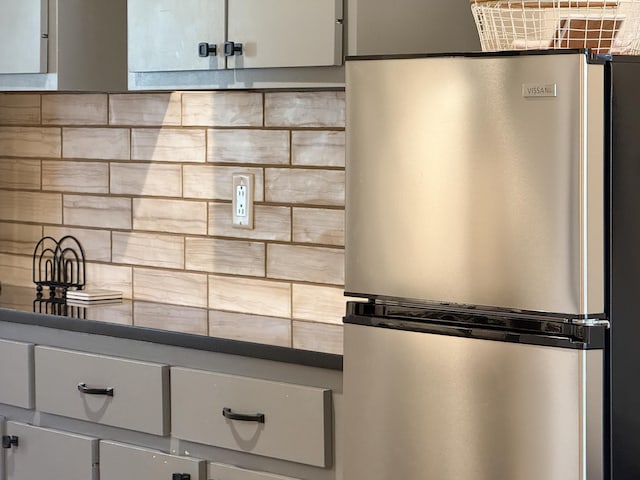 details featuring backsplash and stainless steel refrigerator