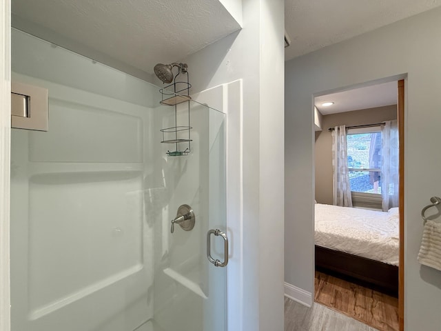 bathroom with hardwood / wood-style flooring, a shower with shower door, and a textured ceiling