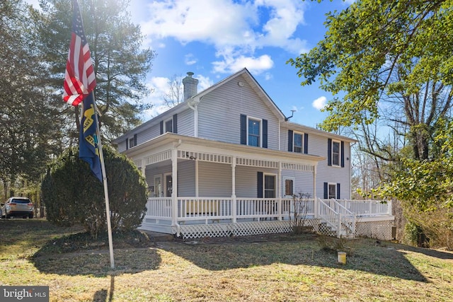 view of front of home featuring a porch, a chimney, and a front lawn