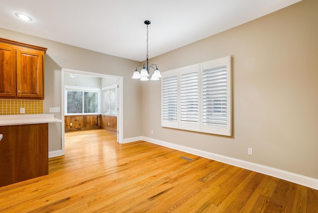 unfurnished dining area with a notable chandelier and light hardwood / wood-style floors