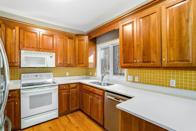 kitchen featuring appliances with stainless steel finishes, light hardwood / wood-style floors, sink, and decorative backsplash