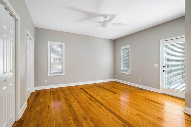 unfurnished bedroom with ceiling fan, hardwood / wood-style floors, and two closets