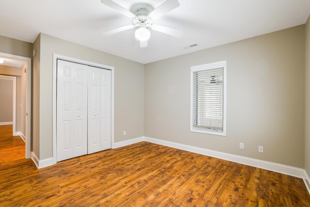 unfurnished bedroom with hardwood / wood-style floors, ceiling fan, and a closet