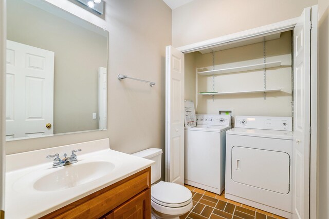 bathroom with vanity, washing machine and clothes dryer, and toilet