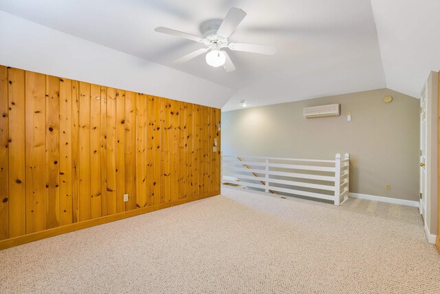 unfurnished room featuring wood walls, lofted ceiling, carpet floors, a wall mounted AC, and ceiling fan