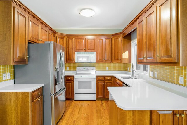 kitchen featuring sink, kitchen peninsula, white appliances, light hardwood / wood-style floors, and backsplash