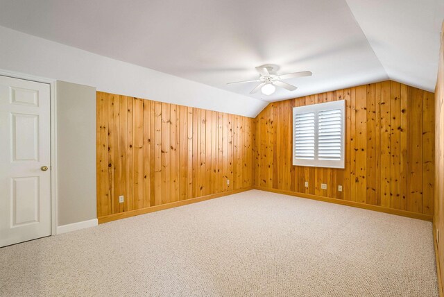 bonus room featuring lofted ceiling, carpet, and wood walls