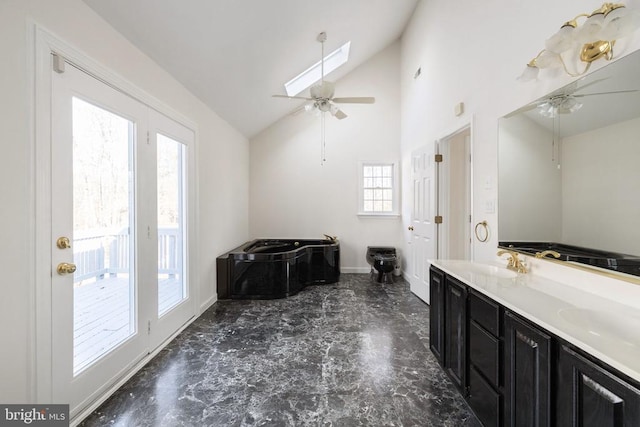 bathroom with a skylight, a bathing tub, ceiling fan, vanity, and high vaulted ceiling