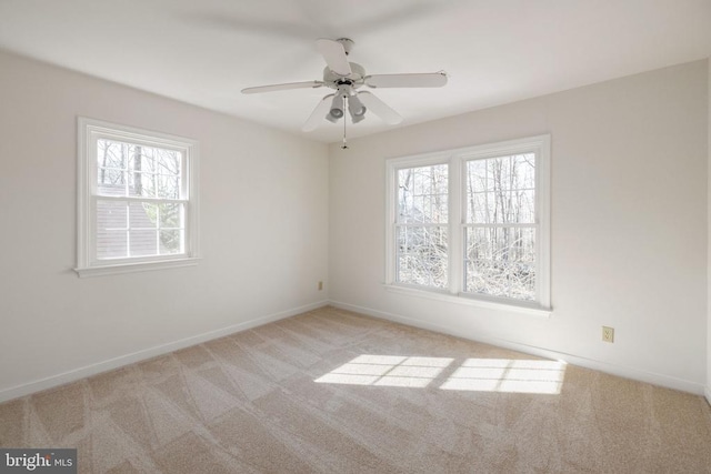 empty room featuring a wealth of natural light, light carpet, and baseboards