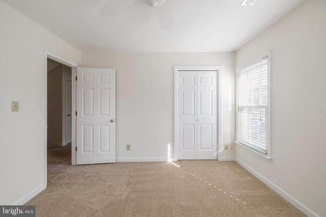 unfurnished bedroom featuring a closet, light colored carpet, and baseboards