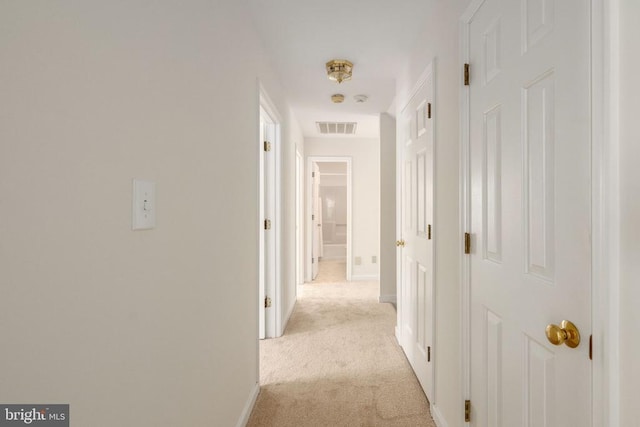 corridor featuring light carpet, visible vents, and baseboards