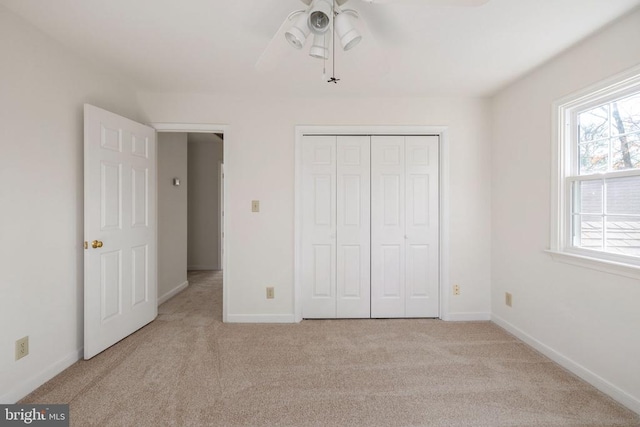 unfurnished bedroom with light carpet, ceiling fan, baseboards, and a closet