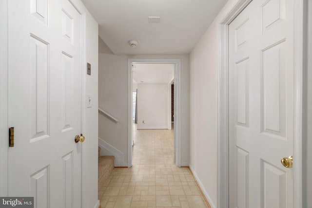 corridor featuring baseboards and stairway