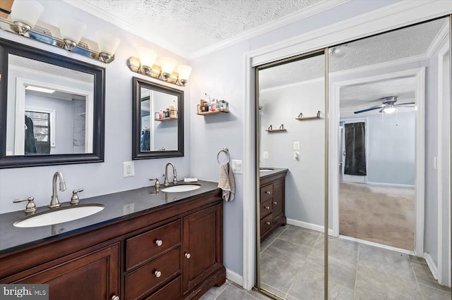 bathroom with double vanity, a ceiling fan, a sink, and a textured ceiling