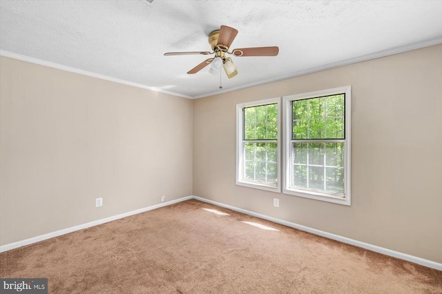 spare room with carpet floors, ornamental molding, baseboards, and a ceiling fan