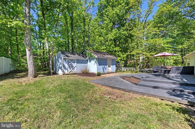 view of yard featuring an outdoor structure, fence, a storage shed, and a wooden deck