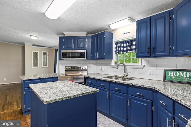 kitchen with a sink, appliances with stainless steel finishes, a kitchen island, and blue cabinetry