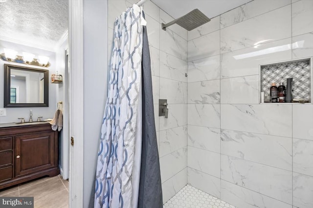 bathroom featuring a textured ceiling, crown molding, vanity, tile patterned floors, and tiled shower