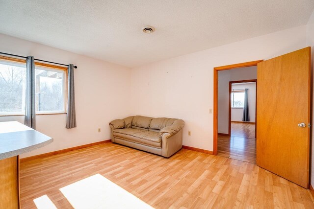 unfurnished living room featuring light hardwood / wood-style flooring and a textured ceiling