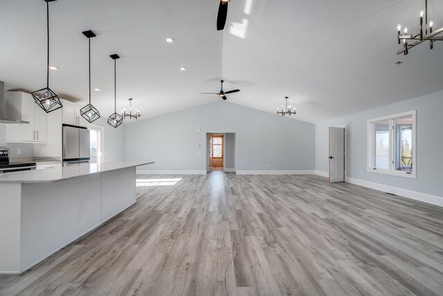 kitchen featuring decorative light fixtures, stainless steel fridge, white cabinets, and range