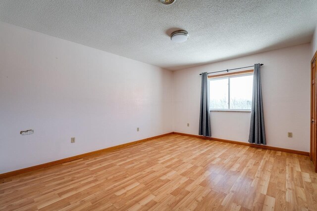 empty room featuring a textured ceiling and light wood-type flooring