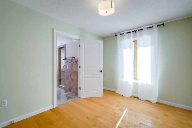 spare room with light hardwood / wood-style flooring and a textured ceiling