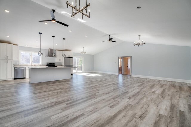 unfurnished living room featuring vaulted ceiling, ceiling fan with notable chandelier, and light hardwood / wood-style flooring