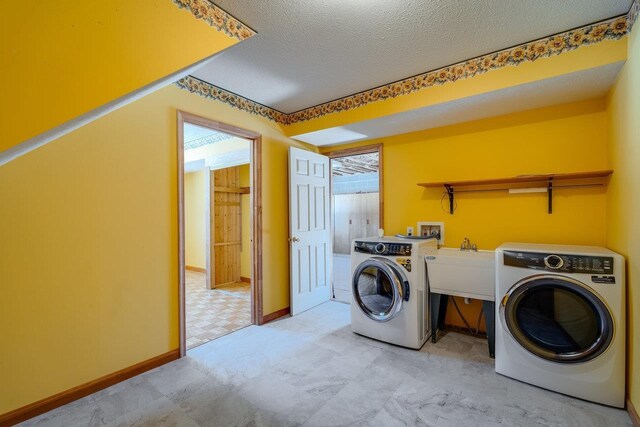 laundry area with washing machine and clothes dryer, sink, and a textured ceiling