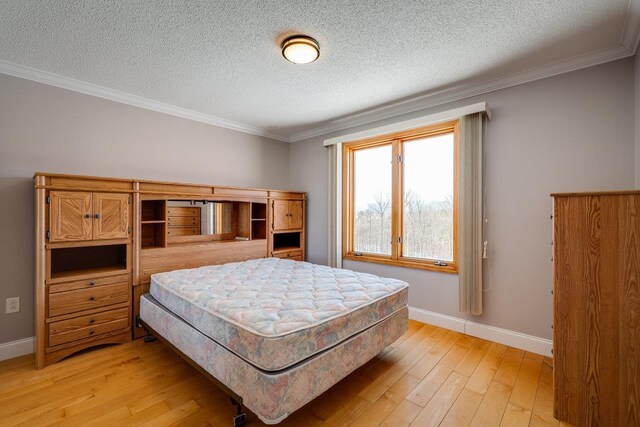 bedroom with ornamental molding, a textured ceiling, and light wood-type flooring