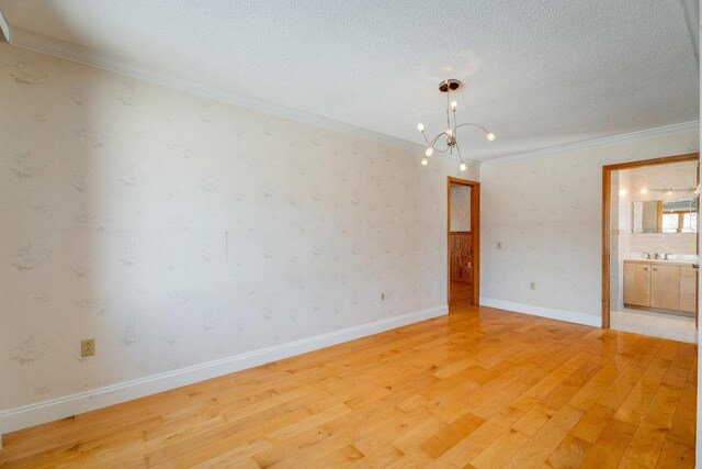 spare room featuring sink, crown molding, light hardwood / wood-style flooring, an inviting chandelier, and a textured ceiling