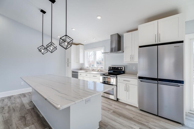 kitchen with a kitchen island, white cabinetry, appliances with stainless steel finishes, and wall chimney exhaust hood