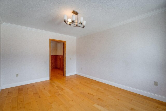 unfurnished room featuring an inviting chandelier, ornamental molding, light hardwood / wood-style floors, and a textured ceiling