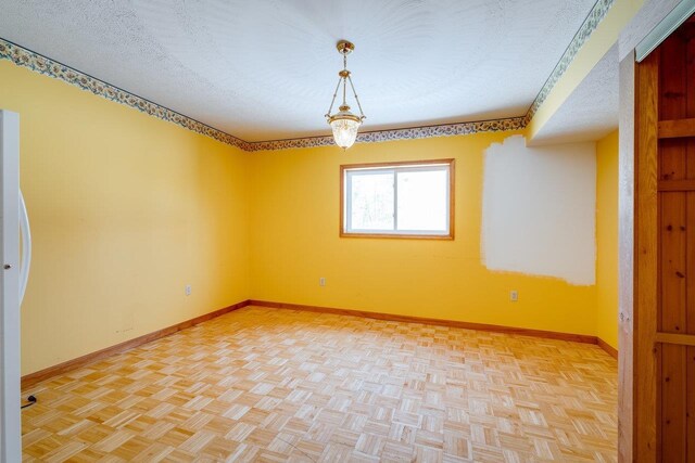 spare room with light parquet flooring and a textured ceiling