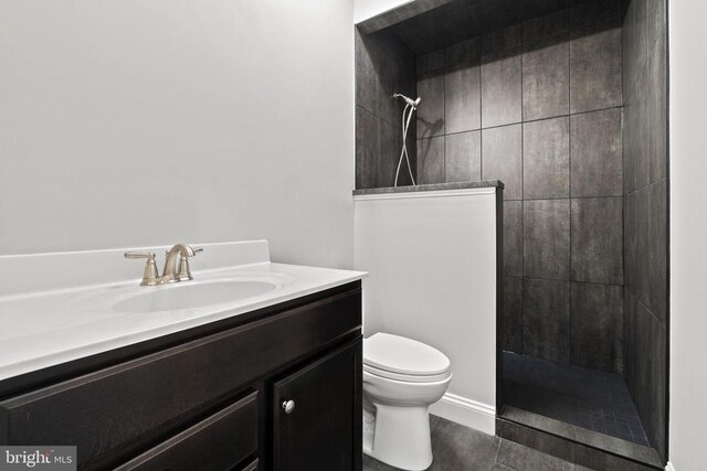 bathroom featuring vanity, tiled shower, and toilet